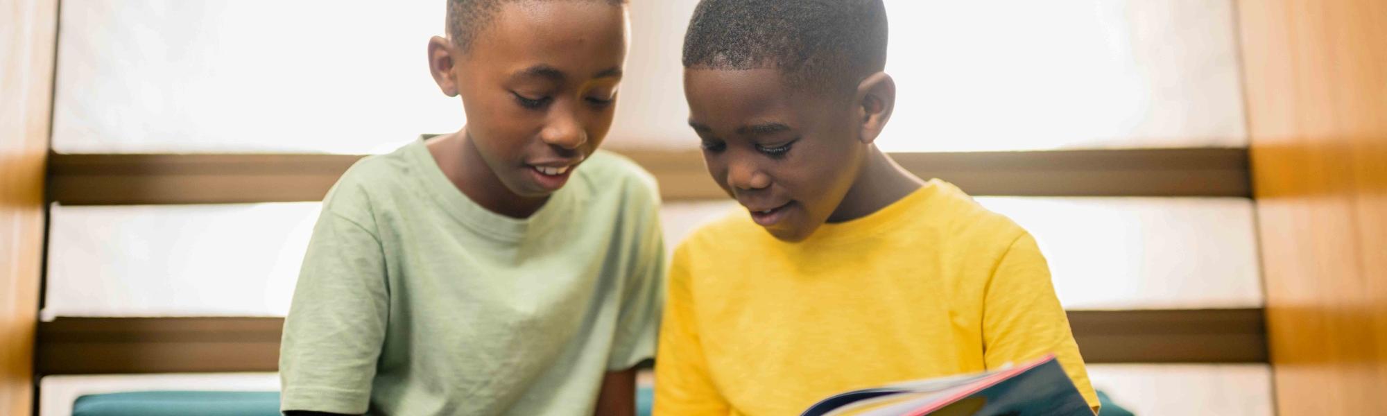 Two young boys reading a book in a building