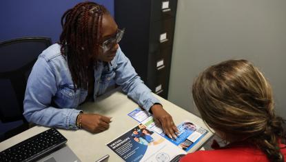 Photo of a family coach assisting a client at a Center for Strong Families. She is showing her information about ways to advance her career.