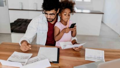 A man sits working with his child in his lap.