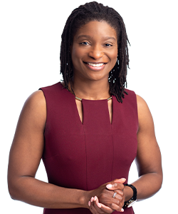Shawan is wearing a maroon top and she is standing in front of a white background. She is smiling for her employee photo.
