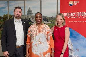 3 individuals standing in front of a sign that says Advocacy Forum & Capitol Hill Day with the US Capitol in the background