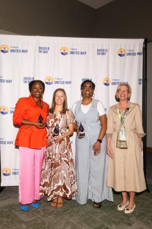Photo of the award winners and keynote speakers standing in front of a step and repeat at the awards luncheon.