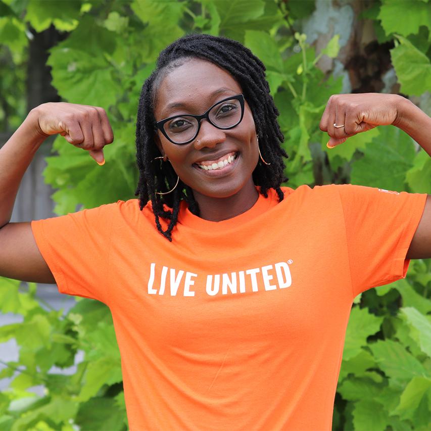 Photo of a woman wearing a shirt that says LIVE UNITED and making muscles