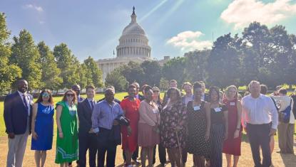 A group of individuals posing for a photo with Capitol Hill in the background